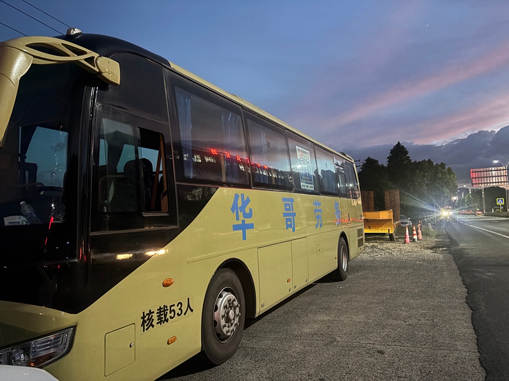 华哥劳务大型空调班车停靠在道路旁，车身印有公司标识